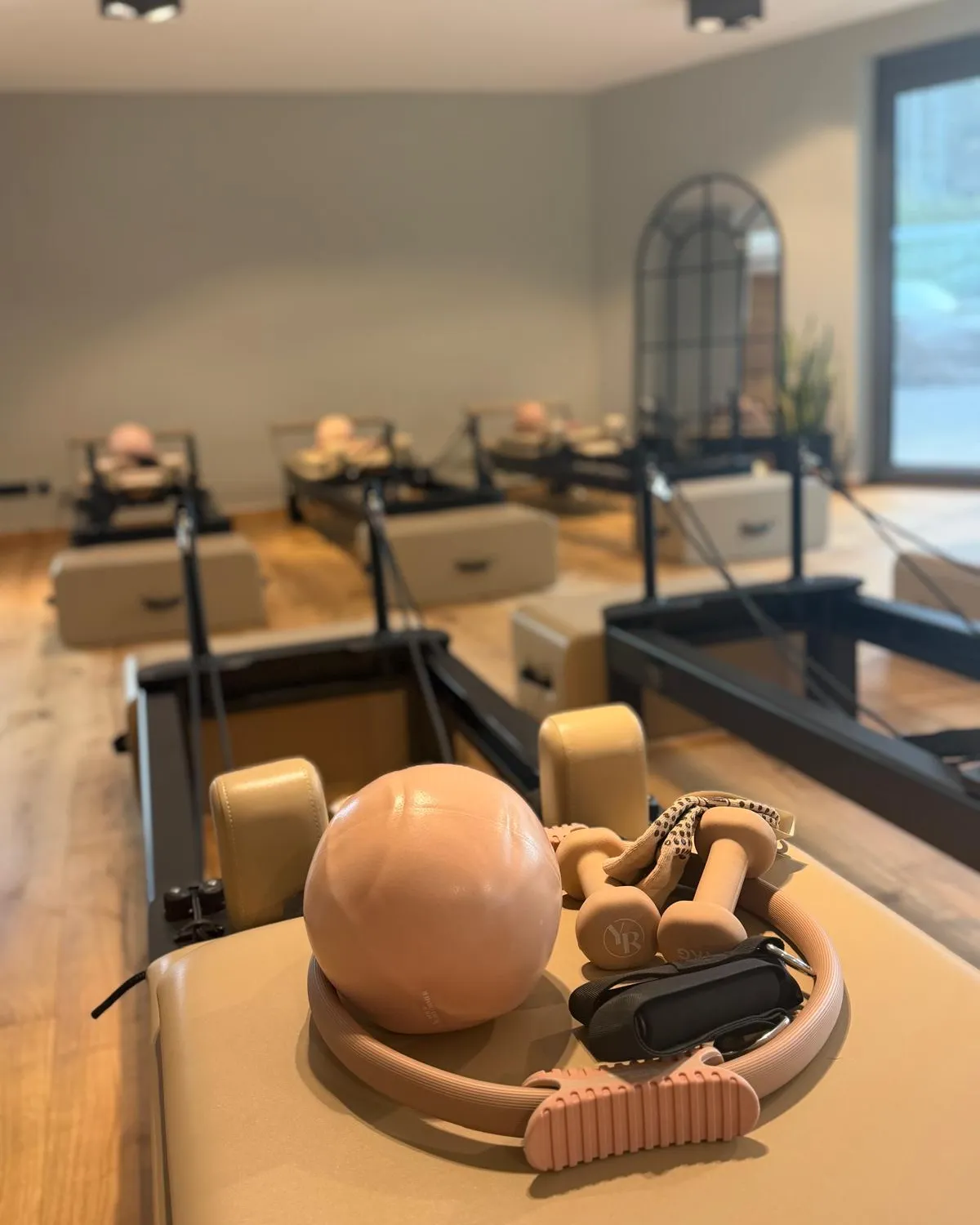 Pilates-Ball, Ring und Hanteln auf einem Reformer, dahinter weitere Reformer